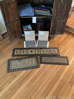 Photo showing wood decor signs GIVE THANKS, CELEBRATE, HARVEST with two Magnolia Home metal signs in original packaging propped behind them