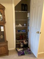 Full view of metal wire shelving rack with painting supplies and tools inside and in front of it