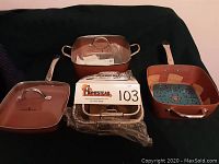 All cookware pieces laid out showing pans, pot with lid, steam basket, rack, manual and sleeve