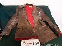 Front view of brown vintage horsehide leather jacket showing red lining and front flap pockets.