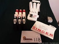 Singer Tiny Serger TS-380 Plus with foot pedal, instruction manual, and 21 thread spools in various colors.