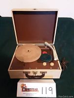 Open portable record player in beige case showing turntable, tonearm, and controls.