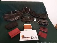 Full view of all items displayed including purses, wallets, and card holders, arranged on green fabric background with lot number card