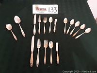 Overall layout of all 17 flatware pieces on black cloth