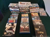 Full view of stacked DVDs and Blu-ray movies on a green fabric surface. Includes movies such as Cradle 2 the Grave, Resident Evil Apocalypse, and 8 Mile.