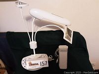 Image showing full view of OttLite crafting lamp with adjustable arms and attached magnifying glass, base with storage compartments, and an unidentified white electronic device.