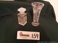 Photo of signed cut crystal vase and decanter on dark cloth background with lot number card