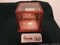 Front view of the glass and wood framed display case on black cloth background.