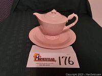 Pink teapot sitting on the round platter with lot number card