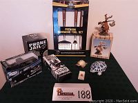 Full lot showing BBQ tool set, 1955 Chevy Stepside model, Phone Jail game, Venom figure, hunter deer sculpture, and decorative turtles.