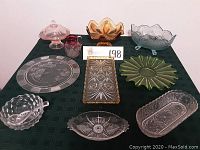 Full view of the 9 glass serving pieces arranged on a dark tablecloth showing their colors and patterns.