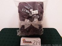 Front view of unopened purple robe in plastic packaging with white bow and retail tags.