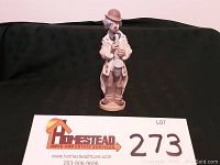 Front view of the porcelain clown figurine playing saxophone with lot number card visible.