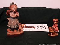 Front view of both figurines on green fabric background with lot label