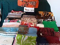 View of assorted folded scarves arranged on a surface showing variety of colors and patterns.