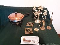 Full view of all items including copper chafing dish, silver candelabra, brass birds, brass trivets, and compact.