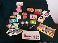 Full overview of lot items including dolls, flip book, film reel, spoons, mirrors, stickers, and packets of patches.