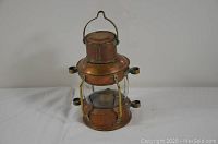 Front view of copper marine lamp showing glass enclosure and brass handle