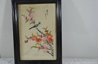 Framed vintage artwork showing bird perched on flowering branch with pink and red flowers in dark wood frame