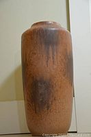 Front view of tall vintage vase showing textured brown matte ceramic body with color variations.