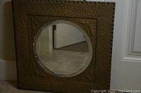 Full view of square mirror with ornate gesso frame and round beveled center
