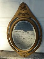Full front view of antique oval mirror showing decorative frame