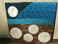 Full view of the quilt showing full composition with five circular embroidery panels against dark blue, teal, and brown background fabric.