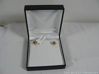 Full view of the pair of gold stud earrings in a jewelry box.