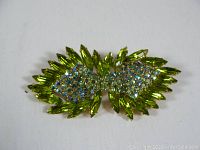 Front view of the vintage rhinestone brooch on a white background showing the arrangement of green marquise and clear with blue rhinestones.