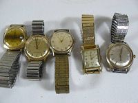 Photo of all five vintage men's watches laid out showing dials and metal expansion bands