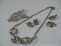 Top down photo showing all four jewelry pieces together on a plain surface.