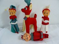 Photo showing three elf figures and one red fabric reindeer, all vintage Christmas decorations.