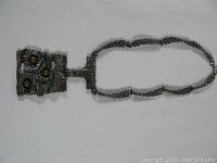 Full view of the necklace laid flat showing the textured silver pendant with three spherical brass accents on a twisted silver chain.