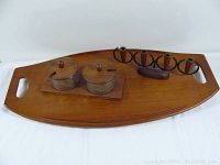 Full view of all three teak items displayed on a white surface: a serving tray, double condiment set, and candle holder.