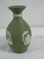 Front view of green Wedgwood vase showing traditional white jasperware relief decoration on matte green background