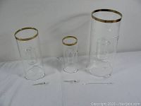 Three clear glass Scandinavian table oil lamps with gold rim accents and wicks on white background
