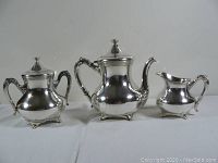 Full view of three-piece silver plated tea set including teapot, creamer, and sugar bowl.