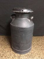 Front view of the vintage steel milk container showing body, handles, and lid.