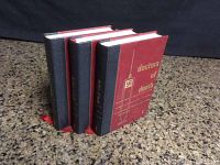 Set of three books with black and red covers standing upright, showing their spines and front cover arrangement.