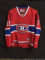 Front view of red Montreal Canadiens hockey jersey with large team logo and number 31 on sleeves.