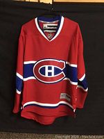 Full front view of red Montreal Canadiens hockey jersey with large team logo on chest, showing style and colors.