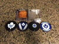 Four Toronto Maple Leafs coasters with clear plastic storage case on granite surface.