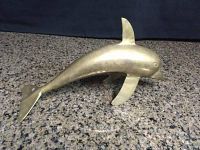 Brass dolphin figurine side view showing smooth brass finish and shape.