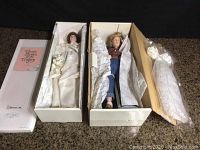 Two boxed porcelain dolls laid out side by side with original boxes, one labeled Danbury Mint 'Prom Dress' and the other an Ellen H. Williams doll wrapped in tissue paper
