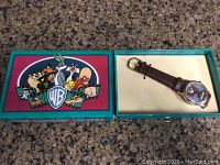 Closed box with colorful Looney Tunes characters on the lid and open box showing the Taz watch with brown leather strap inside.