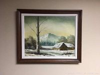 Frontal photo of the oil painting showing the entire artwork and frame, highlighting the snowy cabin scene with a tall tree and mountain in the background