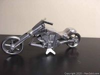 Left side profile view of the polished aluminum motorcycle sculpture showing engine and front wheel detail