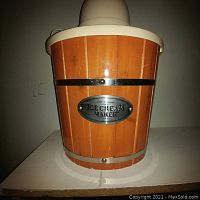 Photo of the ice cream maker showing the wooden bucket design with metal reinforcing bands, and beige motorized top with attached electrical cord.