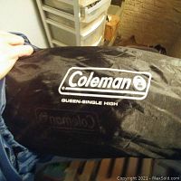 Storage bag showing Coleman logo and product size 'Queen-Single High' printed in white on black fabric.
