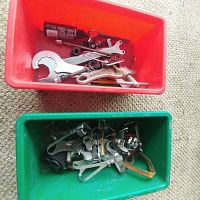 Photo showing two plastic bins filled with assorted bicycle tools and parts including wrenches, chain tools, tire levers, and others.